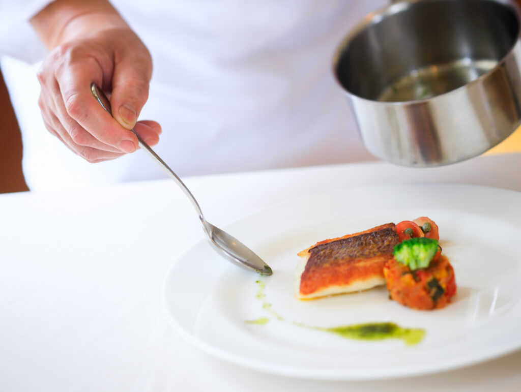 白身魚の料理に、シェフがソースをかけているところ。