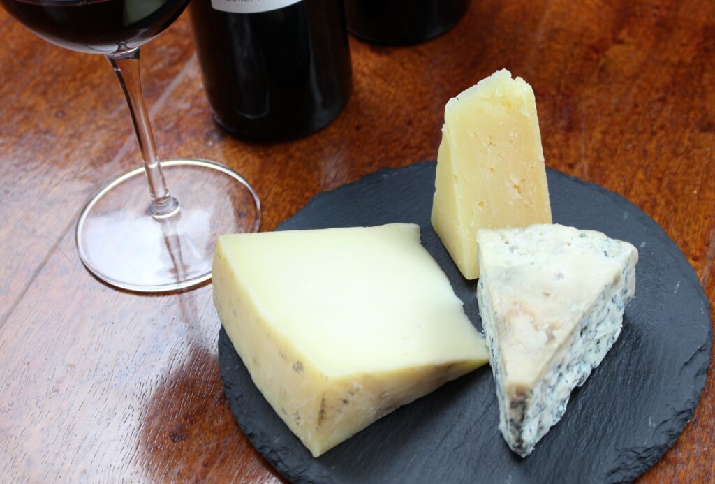 チーズの盛り合わせにグラスに入った赤ワインとボトルの画像