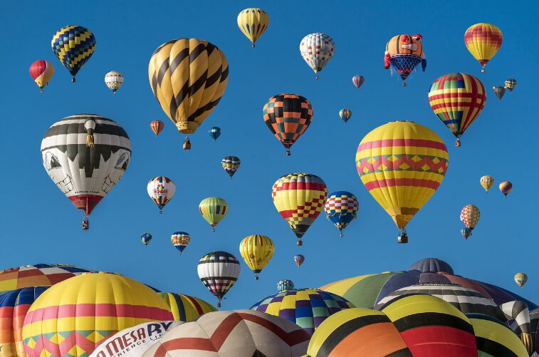 空に色とりどりの熱気球がたくさん浮かんでいる様子。